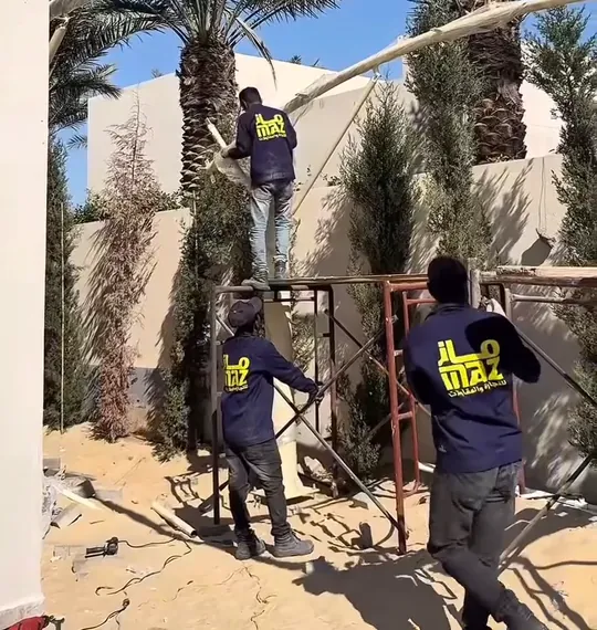 عامل وهيكل معدني خلال تنفيذ مظلة خارجية من أعمال ماز